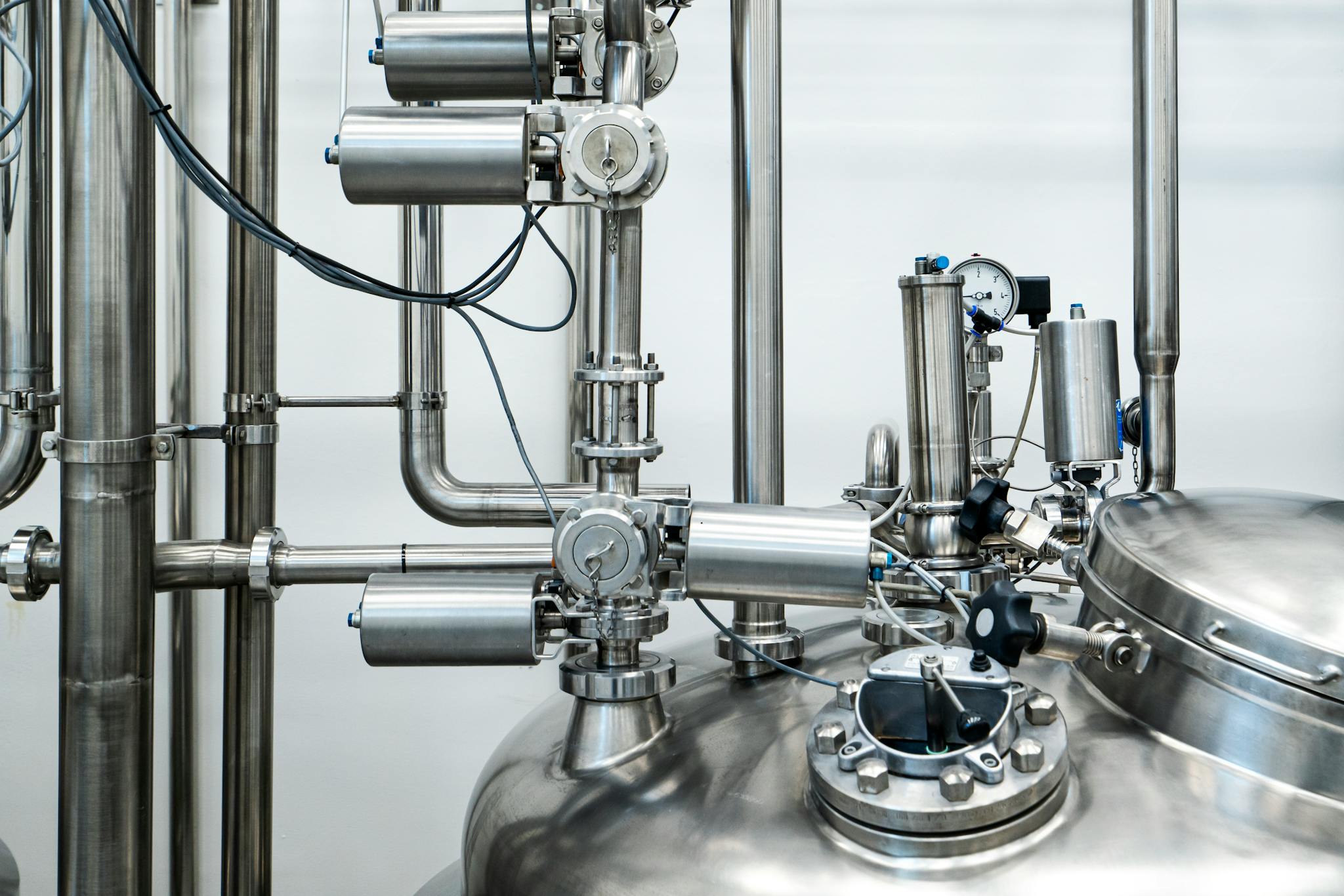 Close-up of stainless steel machinery and pipes in an industrial setting, showcasing modern engineering.