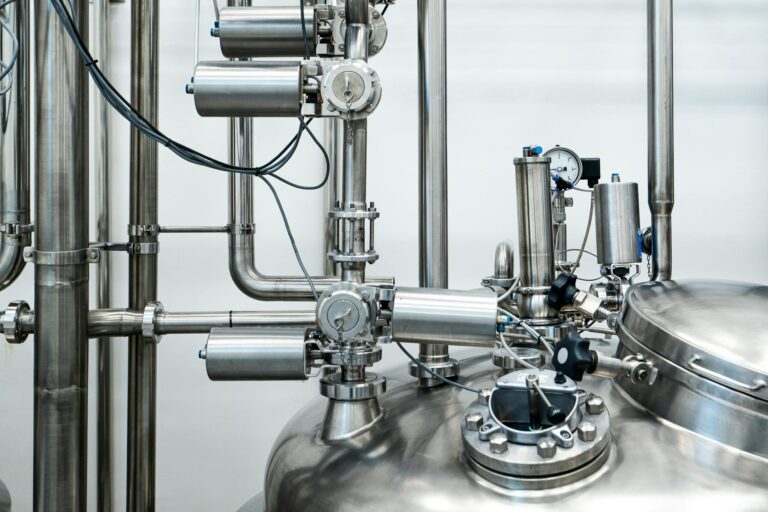 Close-up of stainless steel machinery and pipes in an industrial setting, showcasing modern engineering.